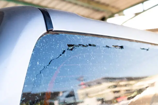 A close-up of a car windshield with multiple cracks and damage visible.