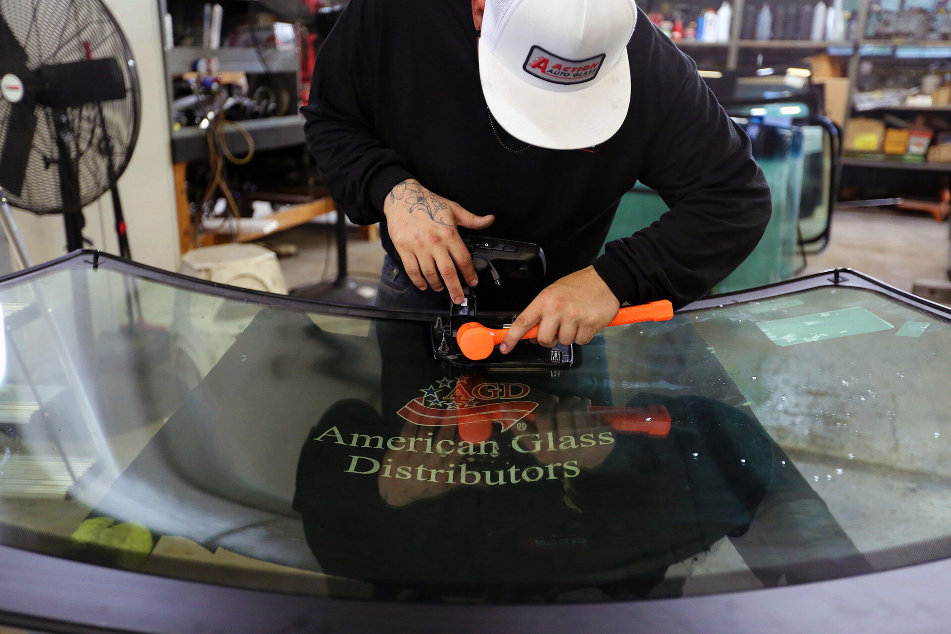 Aaction auto glass technician adjusting rear view mirror on windshield